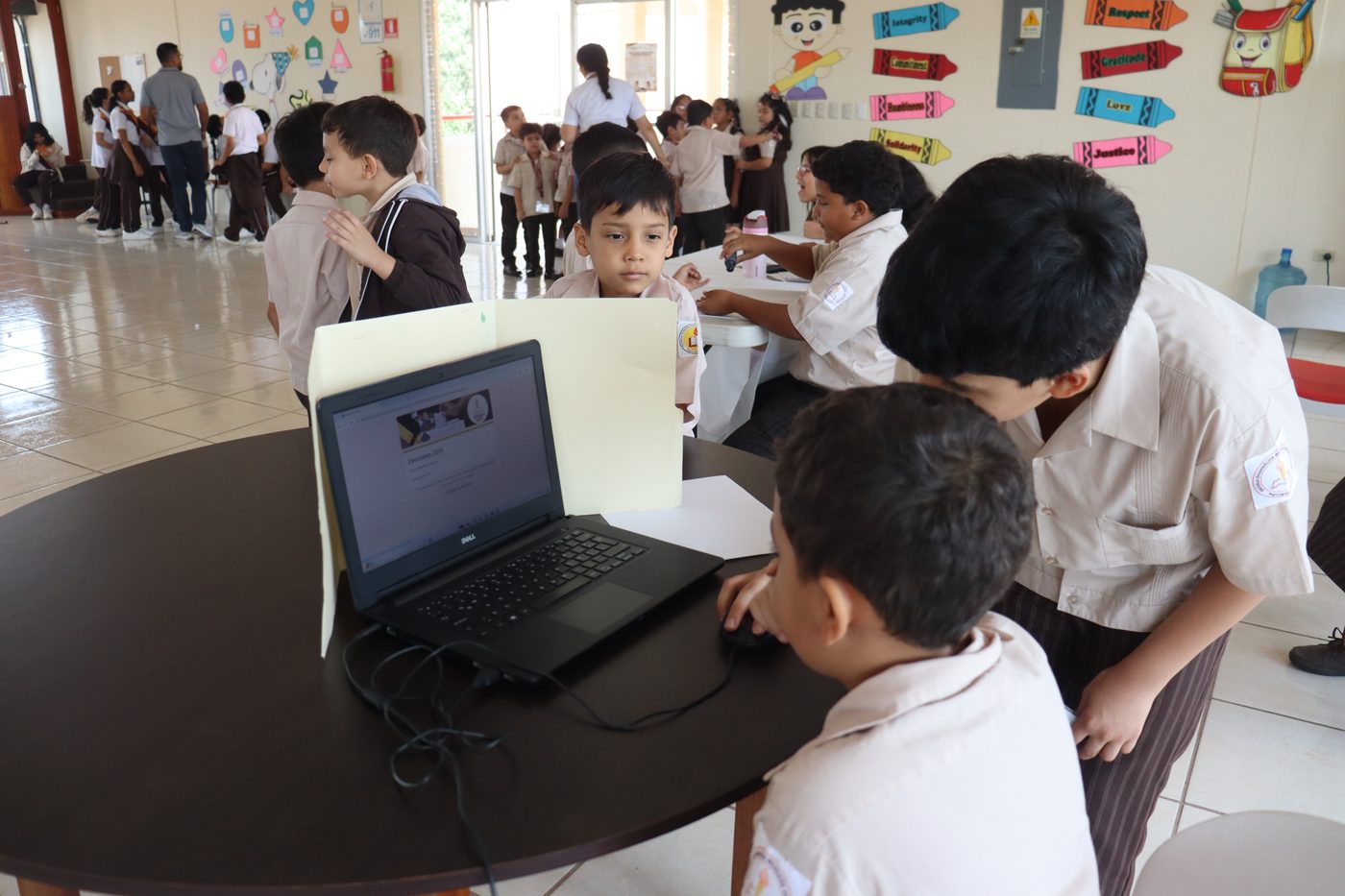 Estudiantes del Centro Educativo Evangélico Virginia Sapp trabajando en computadora junto al mural de valores