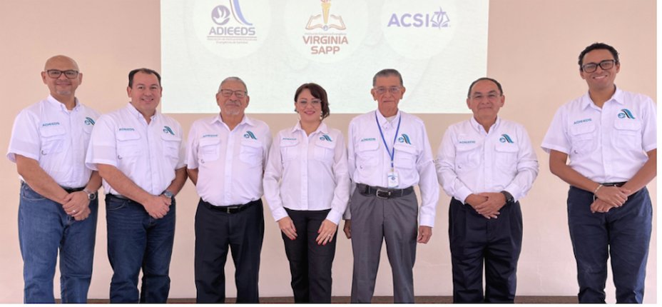 Los siete miembros de la Junta Directiva de ADIEEDS de pie frente a los logotipos de ADIEEDS, Virginia Sapp y ACSI.